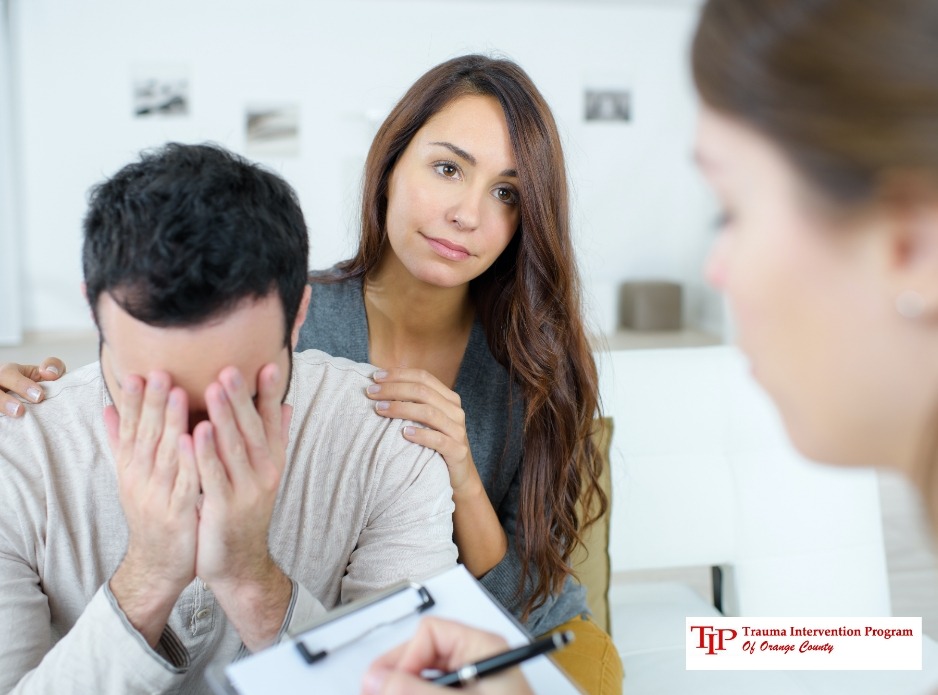 Woman comforting man during therapy session, referencing the Trauma Intervention Program (TIP) NPO