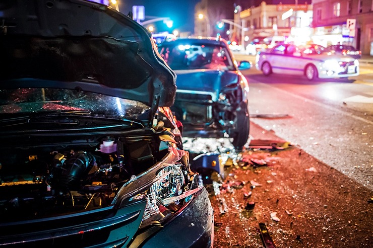 Two cars after an accident on a city street at night in need of a car accident lawyer