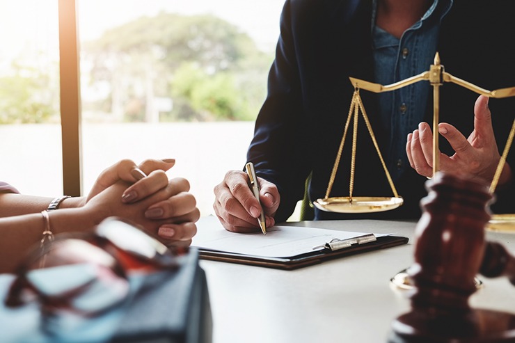 Two obscured individuals at a table discussing a personal injury case next to a gavel and scale