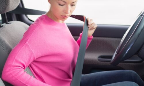 girl putting on a seat belt to avoid seat belt injuries